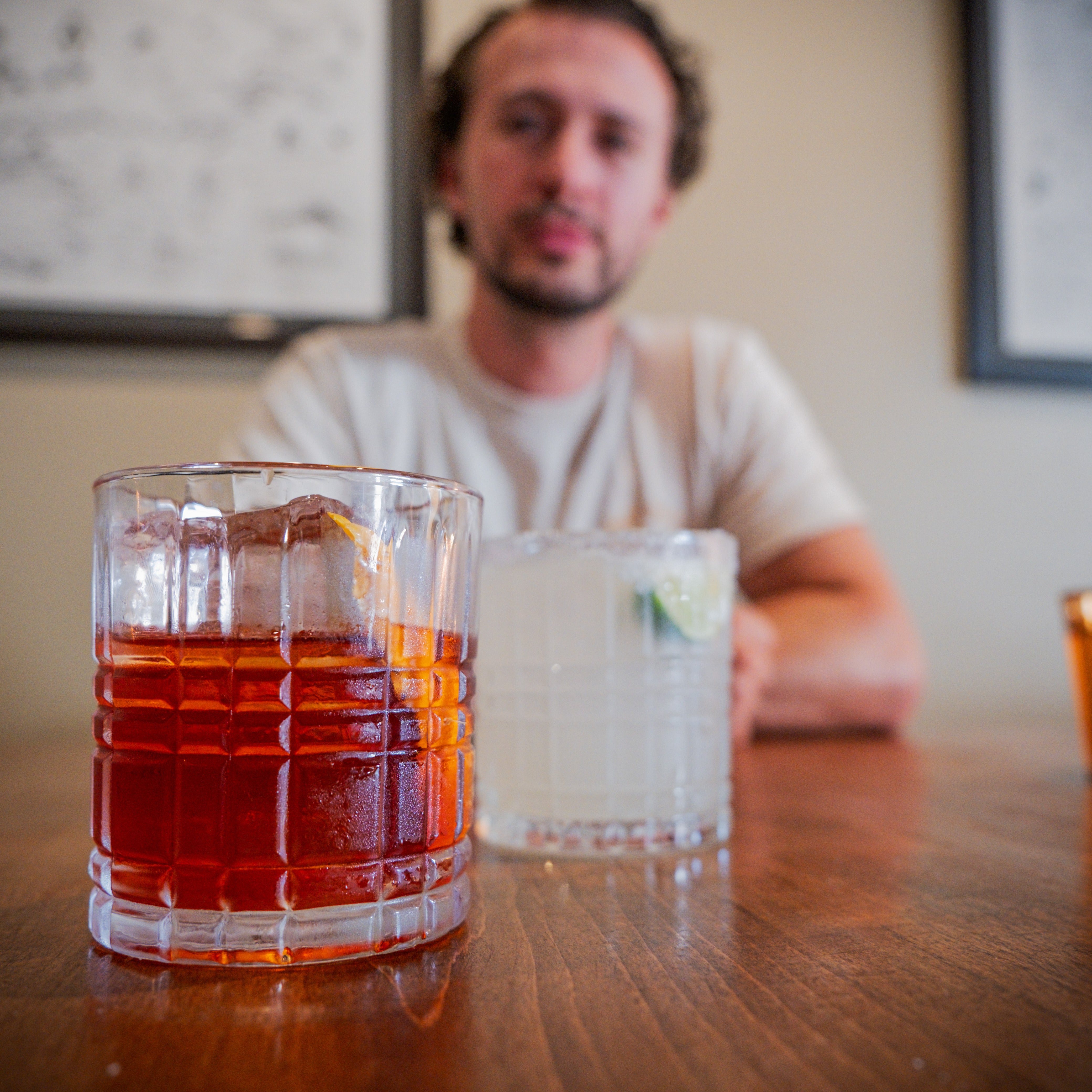 Two glasses of drinks on a table with a blurred person in the background